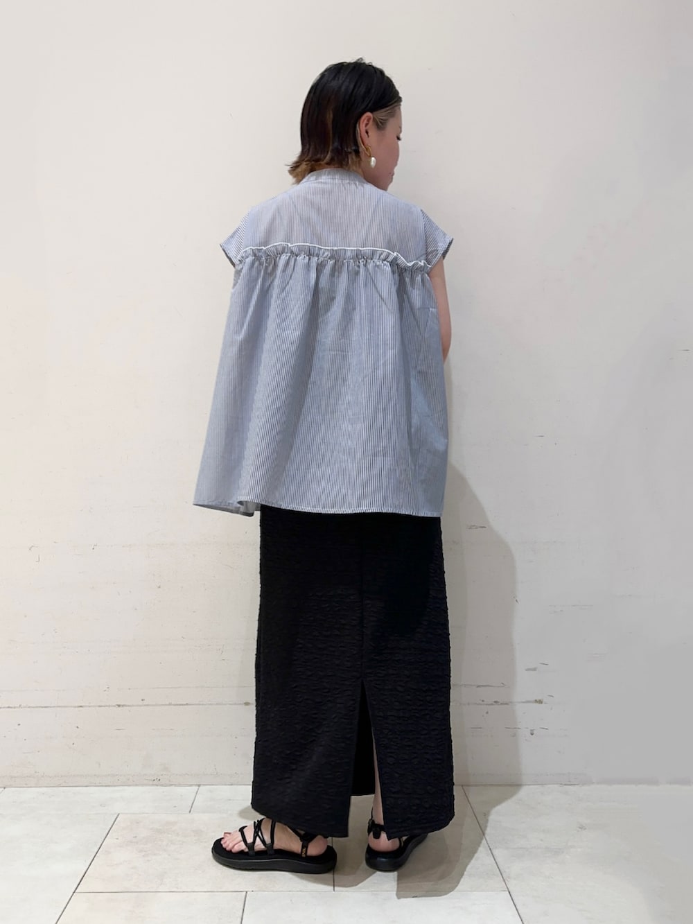 ブルー系のシャツ/ブラウス、ブラック系のスカート、ホワイト系のハンドバッグを着用したレディースの春コーディネートの3枚目の写真