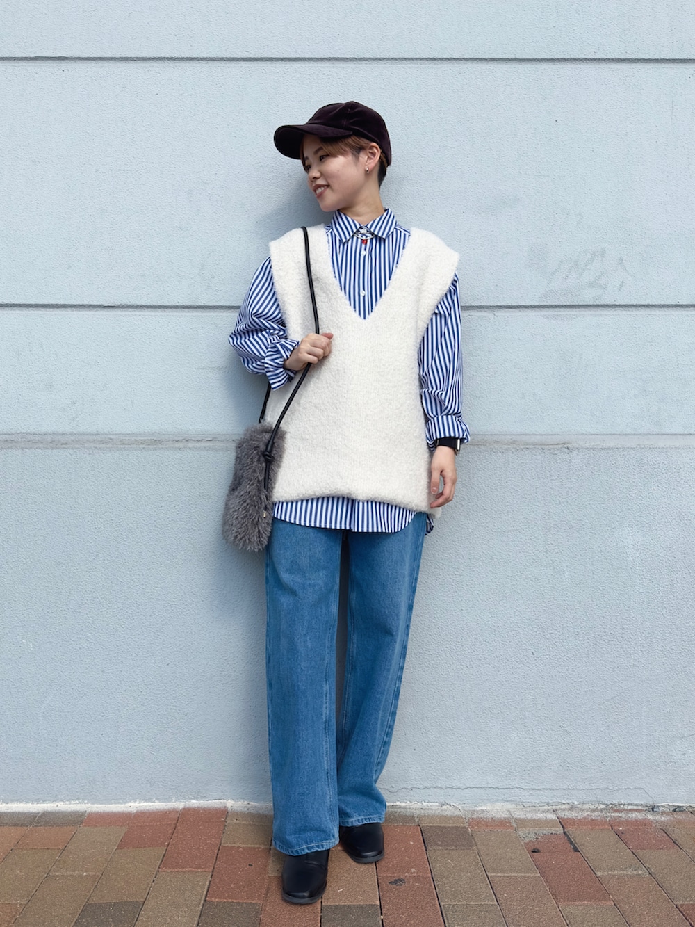 ブルー系のデニムパンツ、ホワイト系のベスト、グレー系のハンドバッグを着用したレディースの秋コーディネートの3枚目の写真