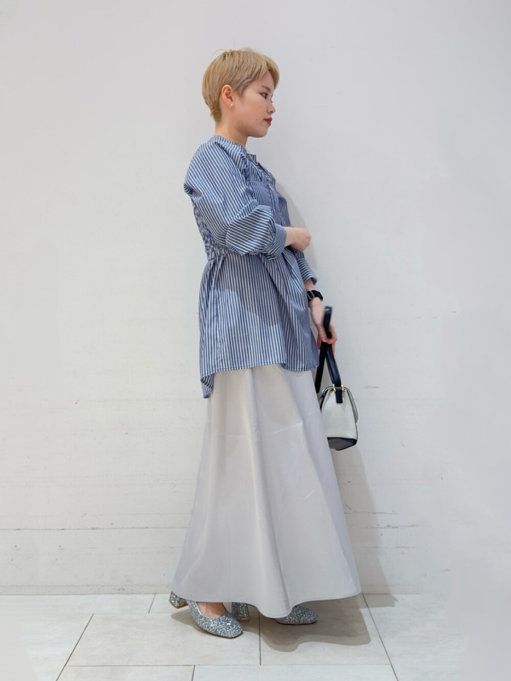 ブルー系のシャツ/ブラウス、シルバー系のスカート、ブラック系のハンドバッグを着用したレディースの春コーディネートの2枚目の写真