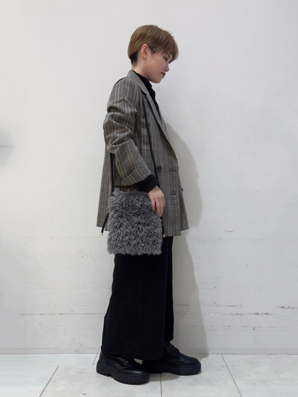 グレー系のノーカラージャケット、グレー系のハンドバッグ、ブラック系のスカートを着用したレディースの秋コーディネートの3枚目の写真