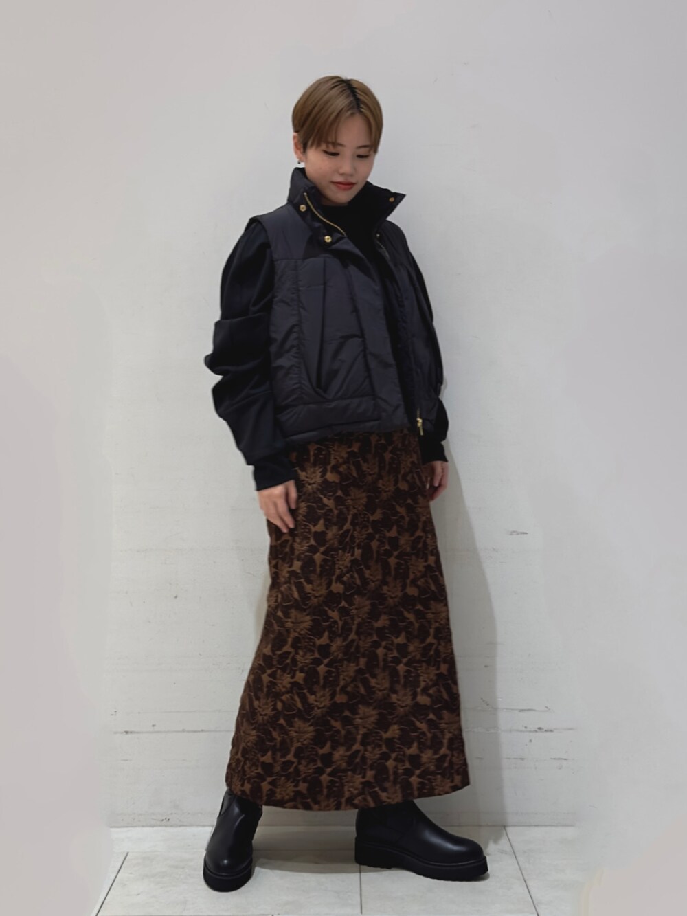 ブラック系のTシャツ/カットソー、ブラック系のベスト、ブラウン系のスカートを着用したレディースの秋コーディネートの2枚目の写真