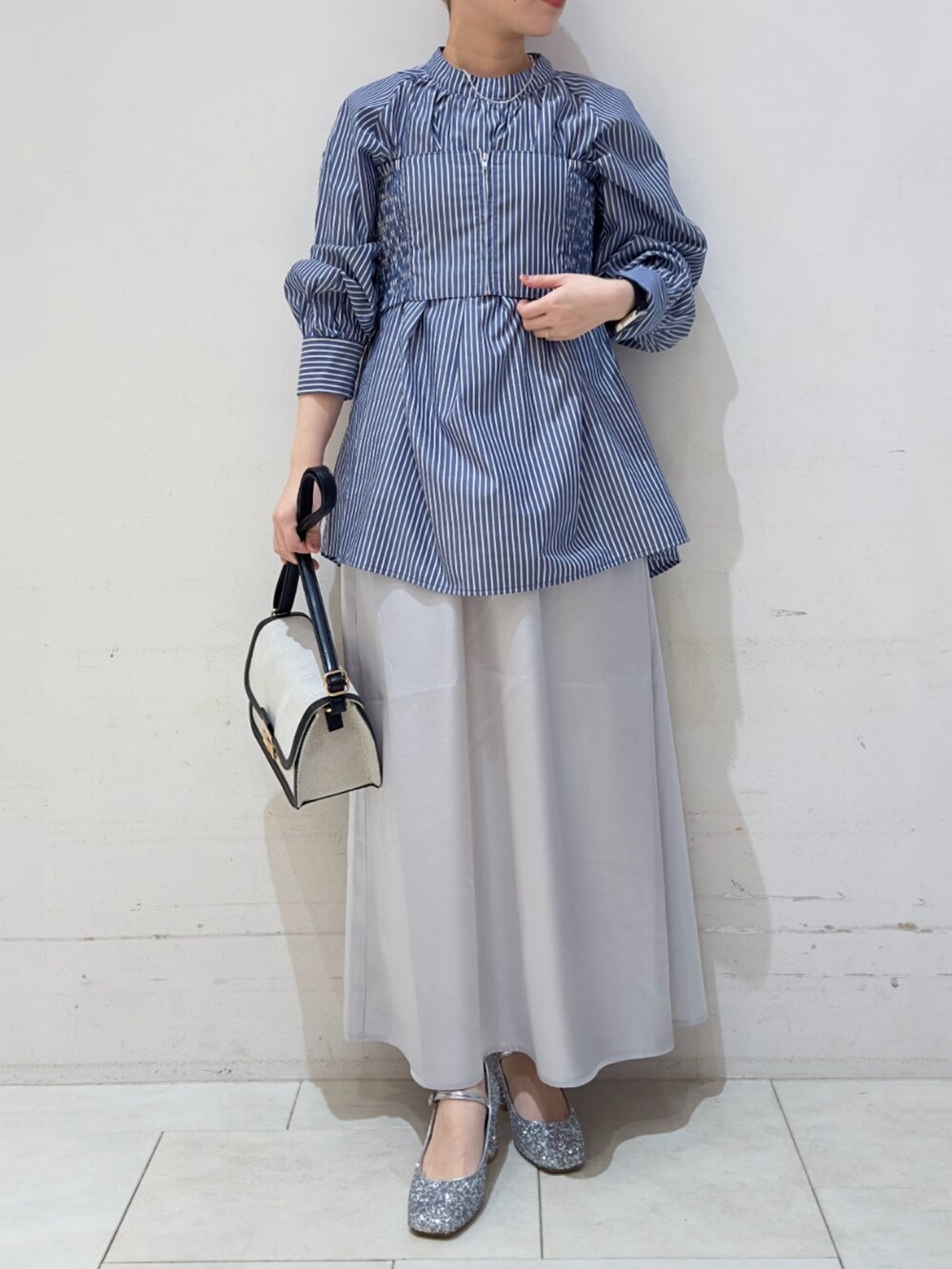 ブルー系のシャツ/ブラウス、シルバー系のスカート、ブラック系のハンドバッグを着用したレディースの春コーディネートの3枚目の写真
