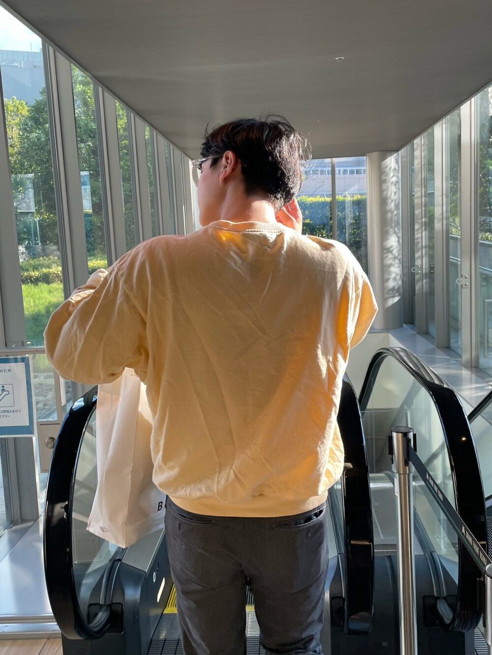 イエロー系のスウェット、グレー系のチノパンツを着用したメンズの秋コーディネートの2枚目の写真