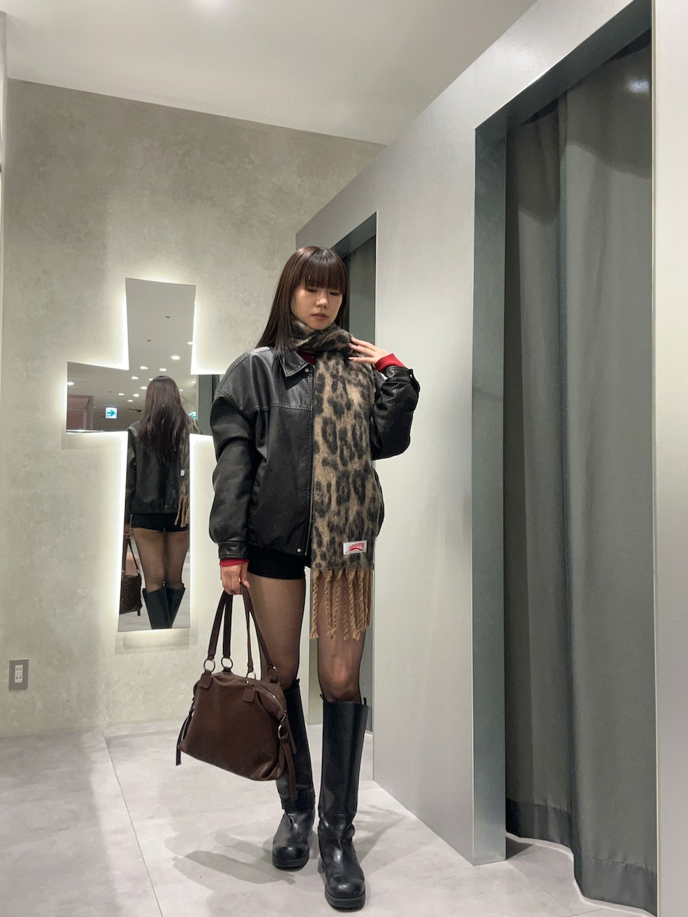 ブラック系のブルゾン、ブラウン系のショルダーバッグ、ブラウン系のマフラーを着用したレディースの冬コーディネートの2枚目の写真