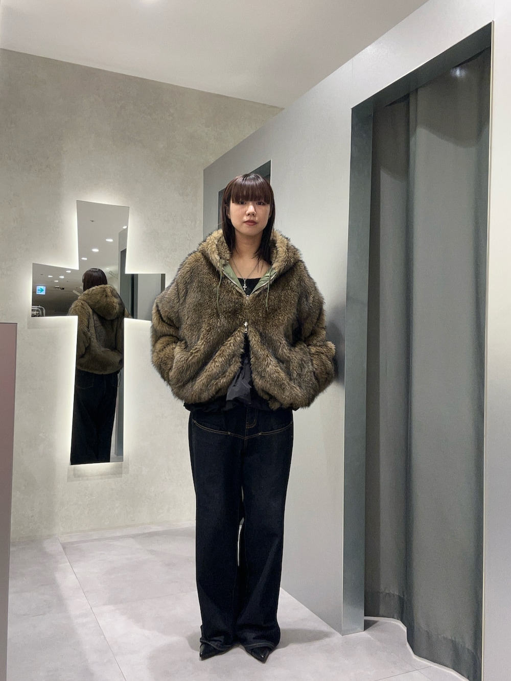 ブルー系のデニムパンツ、ブラック系のワンピース、グリーン系のブルゾンを着用したレディースの秋コーディネートの2枚目の写真