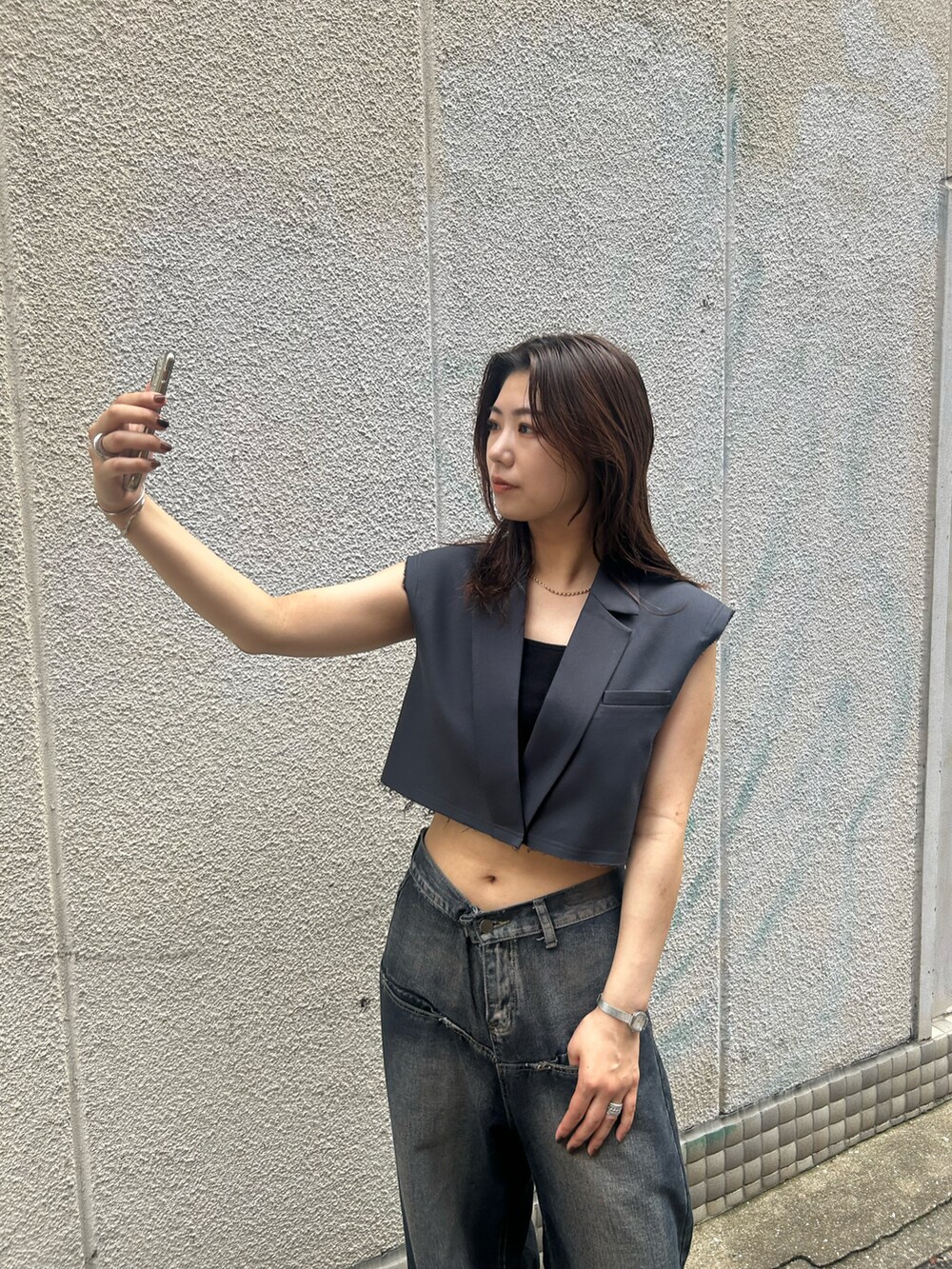 ブルー系のデニムパンツ、グレー系のベストを着用したレディースの夏コーディネートの3枚目の写真