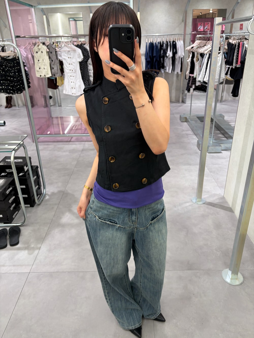 ブルー系のデニムパンツ、ベージュ系のベスト、ブラウン系のタンクトップを着用したレディースの夏コーディネートの2枚目の写真