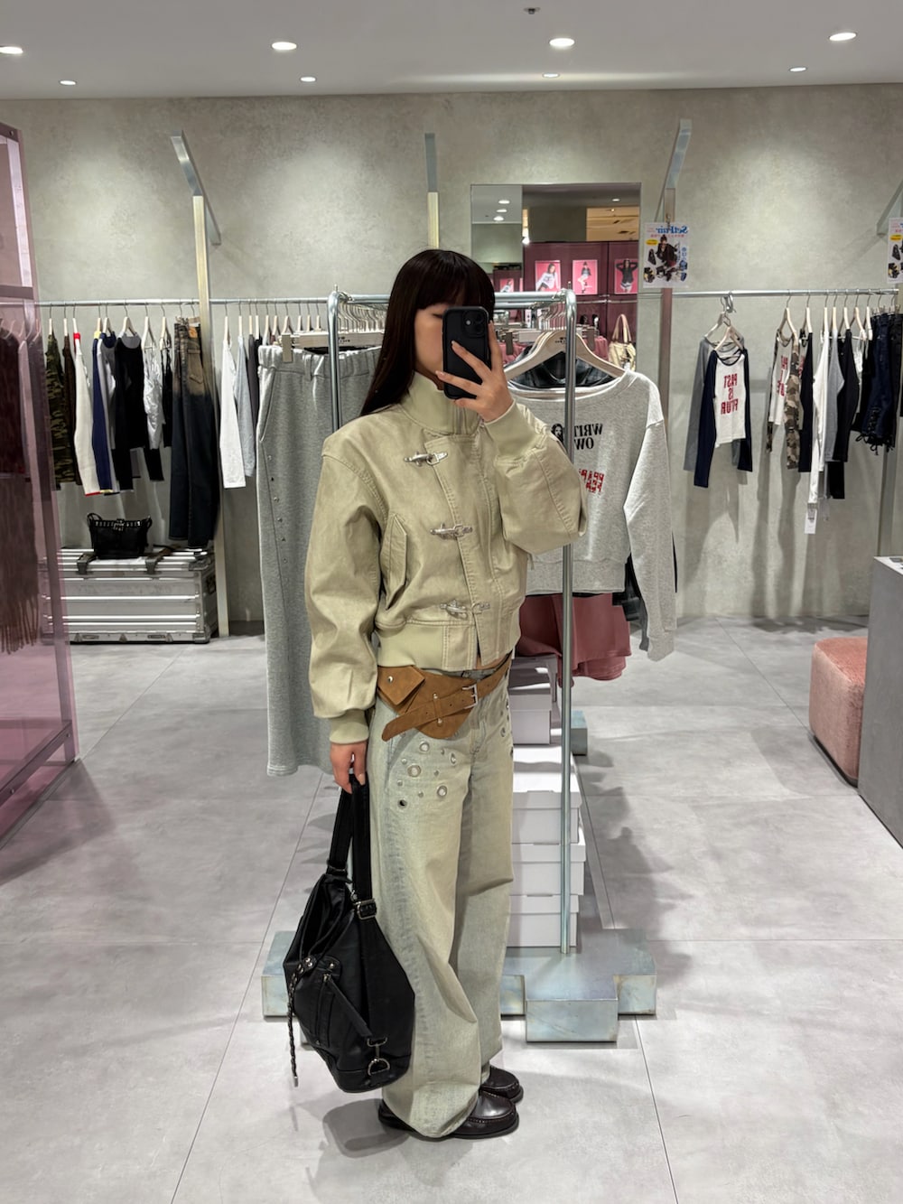 ブルー系のデニムパンツ、ホワイト系のブルゾン、ブラック系のショルダーバッグを着用したレディースの冬コーディネートの2枚目の写真