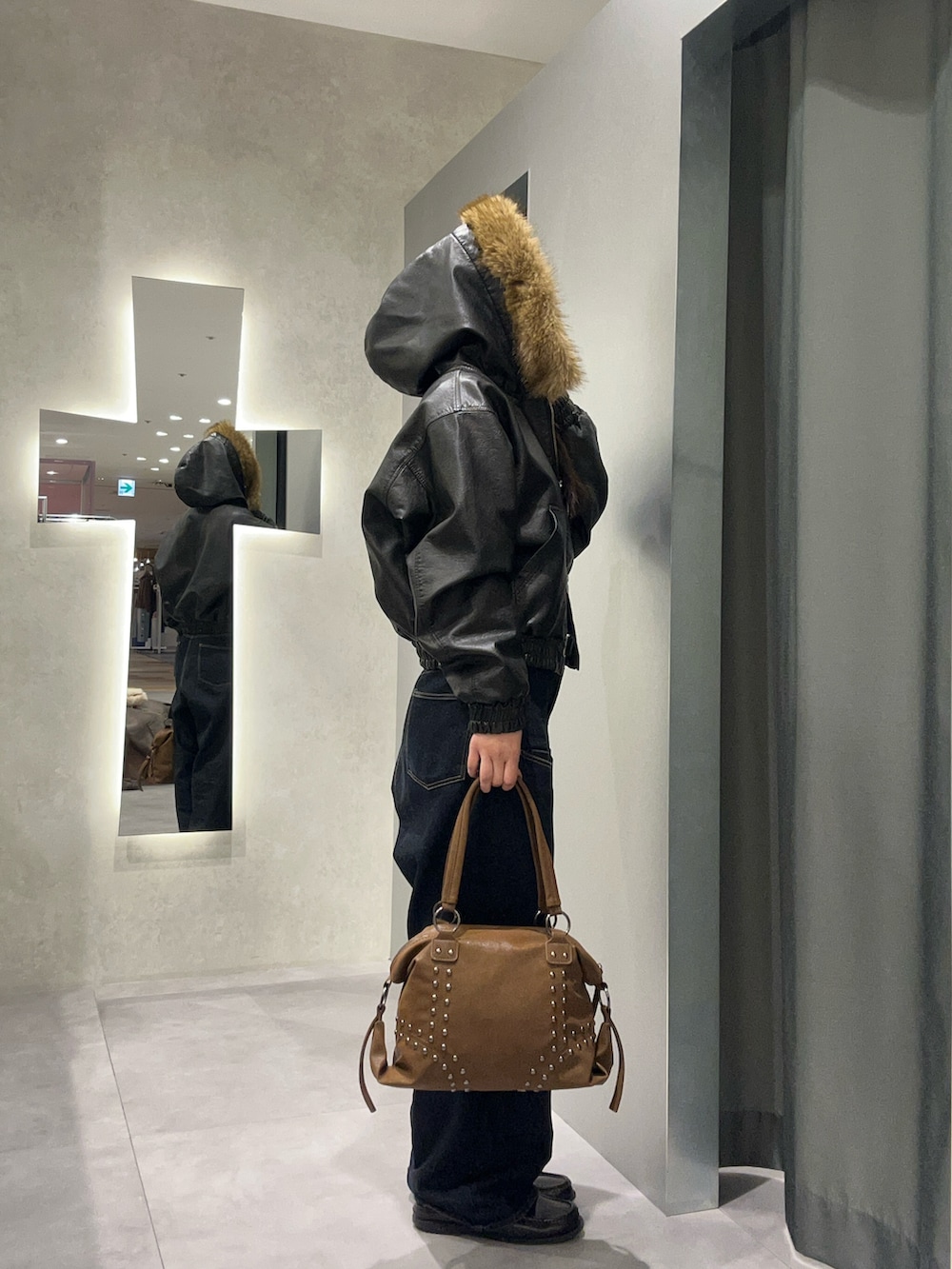 ブラック系のブルゾン、ブルー系のデニムパンツ、ブラウン系のショルダーバッグを着用したレディースの冬コーディネートの2枚目の写真