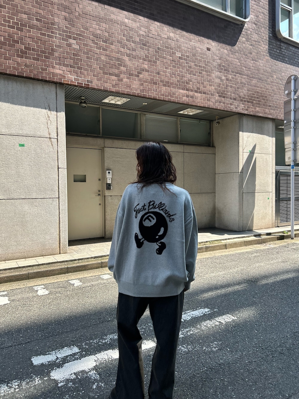 グレー系のニット/セーター、ブラウン系のデニムパンツを着用したレディースの秋コーディネートの2枚目の写真