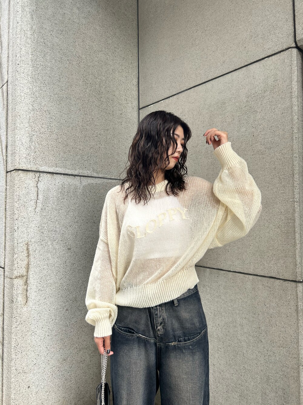 ブルー系のデニムパンツ、ホワイト系のニット/セーター、ブラック系のショルダーバッグを着用したレディースの秋コーディネートの2枚目の写真