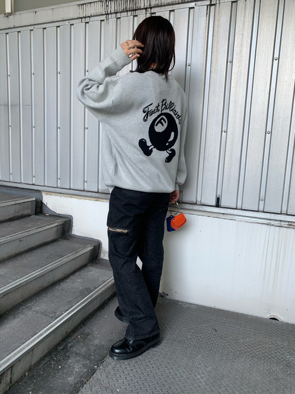 グレー系のニット/セーター、シルバー系のショルダーバッグ、ブラック系のデニムパンツを着用したレディースの夏コーディネートの2枚目の写真