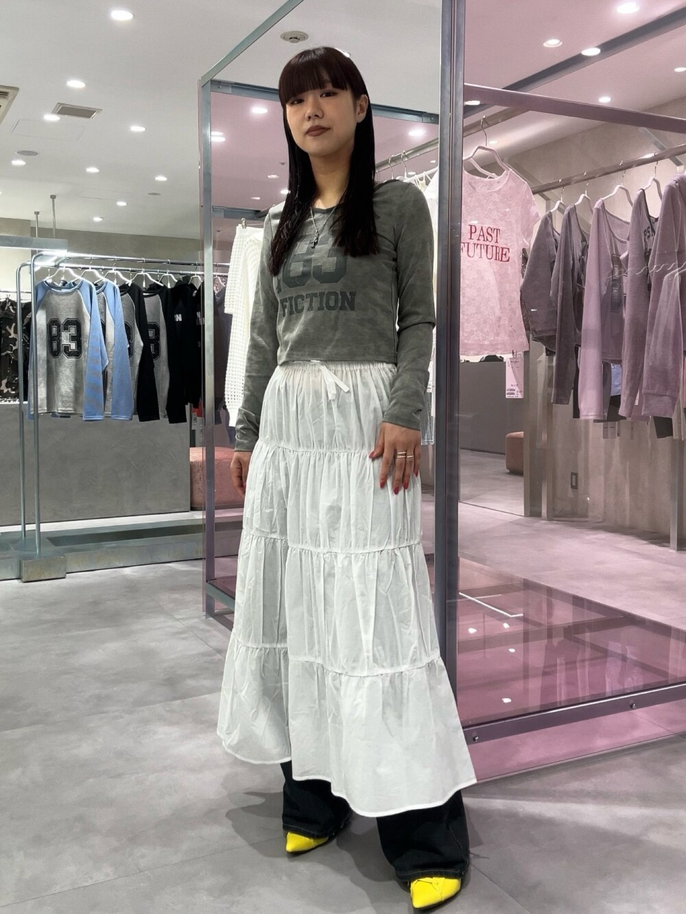 ホワイト系のスカート、イエロー系のパンプス、グレー系のTシャツ/カットソーを着用したレディースの春コーディネートの2枚目の写真