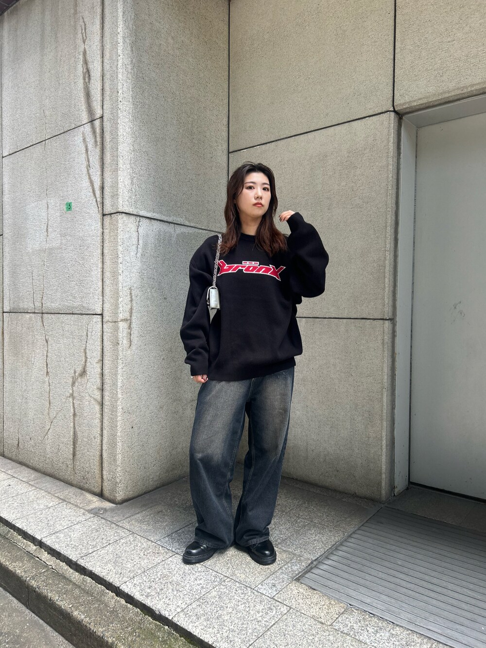 ブルー系のデニムパンツ、ブラック系のニット/セーター、シルバー系のショルダーバッグを着用したレディースの夏コーディネートの2枚目の写真