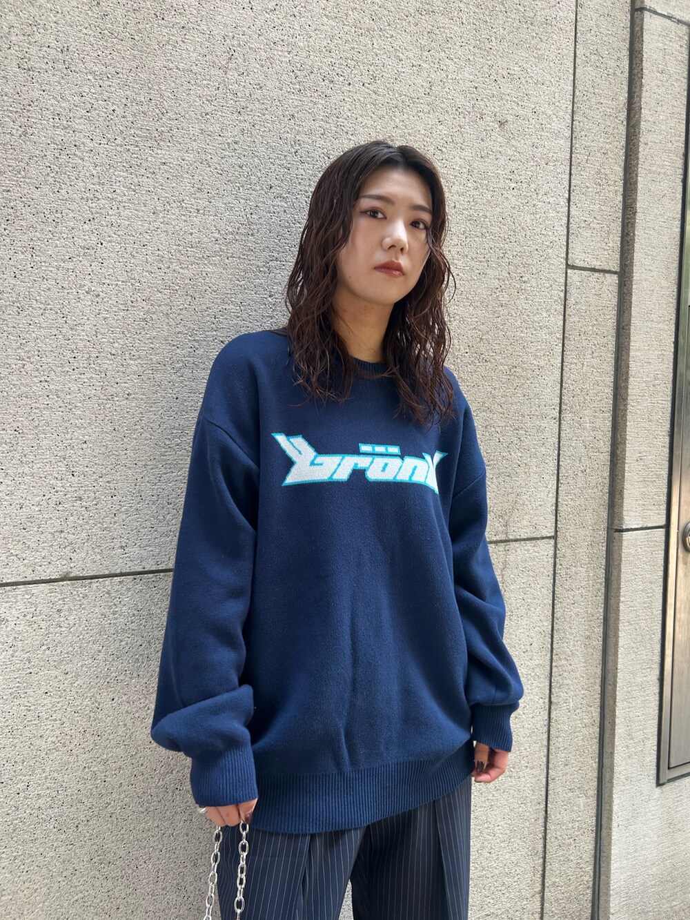 ブルー系のスラックス、ブルー系のニット/セーター、シルバー系のハンドバッグを着用したレディースの夏コーディネートの3枚目の写真