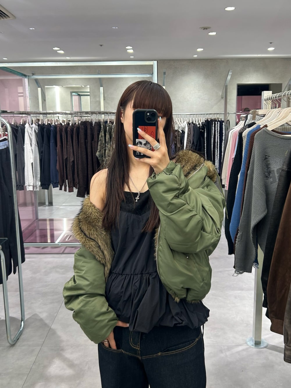 ブルー系のデニムパンツ、ブラック系のワンピース、グリーン系のブルゾンを着用したレディースの秋コーディネートの3枚目の写真