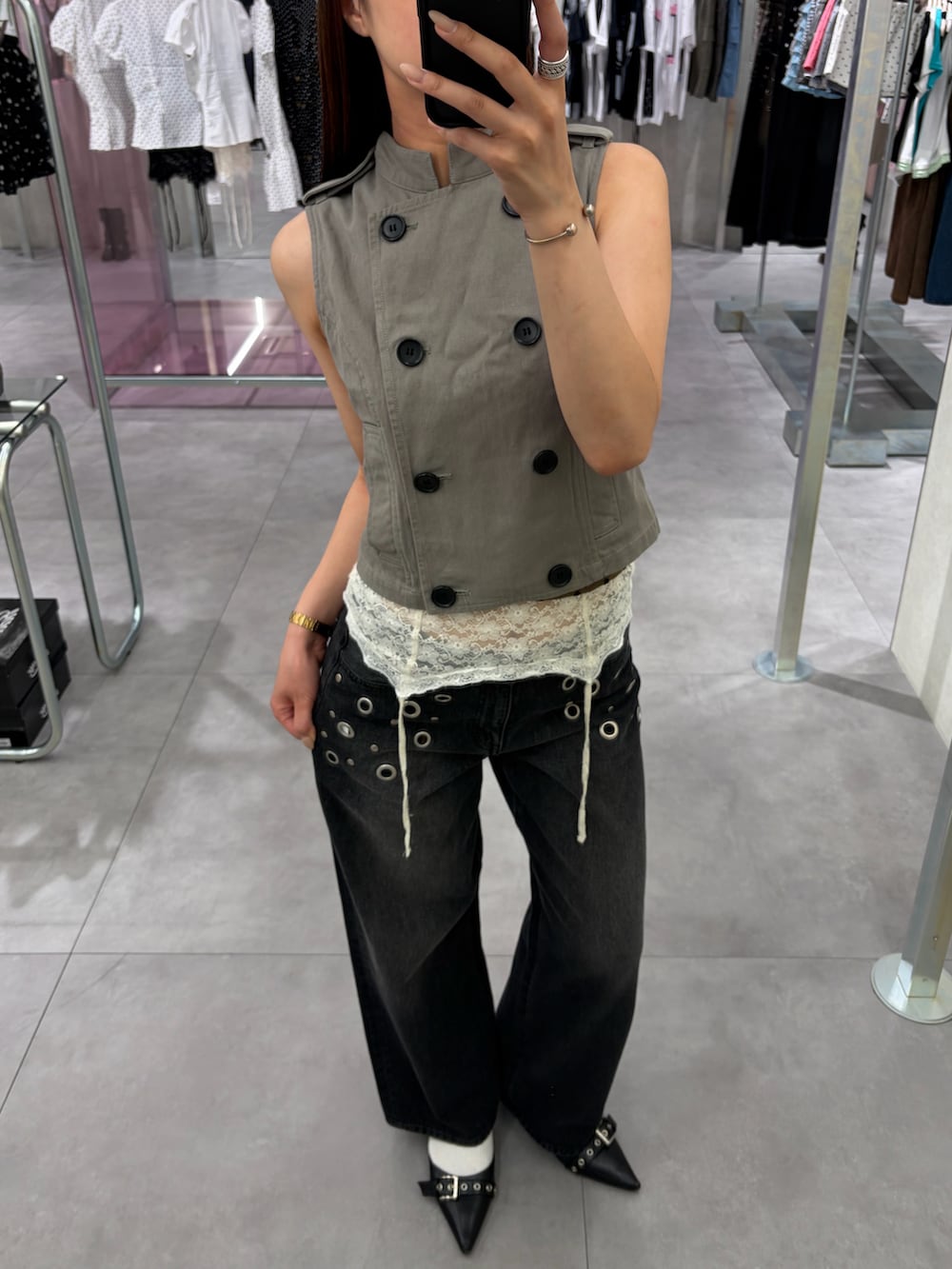 ベージュ系のベスト、ブラック系のデニムパンツ、ホワイト系のキャミソールを着用したレディースの夏コーディネートの2枚目の写真
