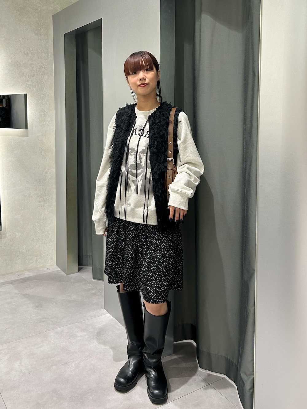 ブラック系のベスト、ホワイト系のスウェット、ホワイト系のスカートを着用したレディースの秋コーディネートの2枚目の写真