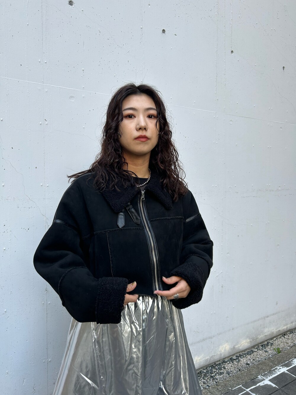 ブラック系のムートンコート、シルバー系のスカートを着用したレディースの秋コーディネートの4枚目の写真