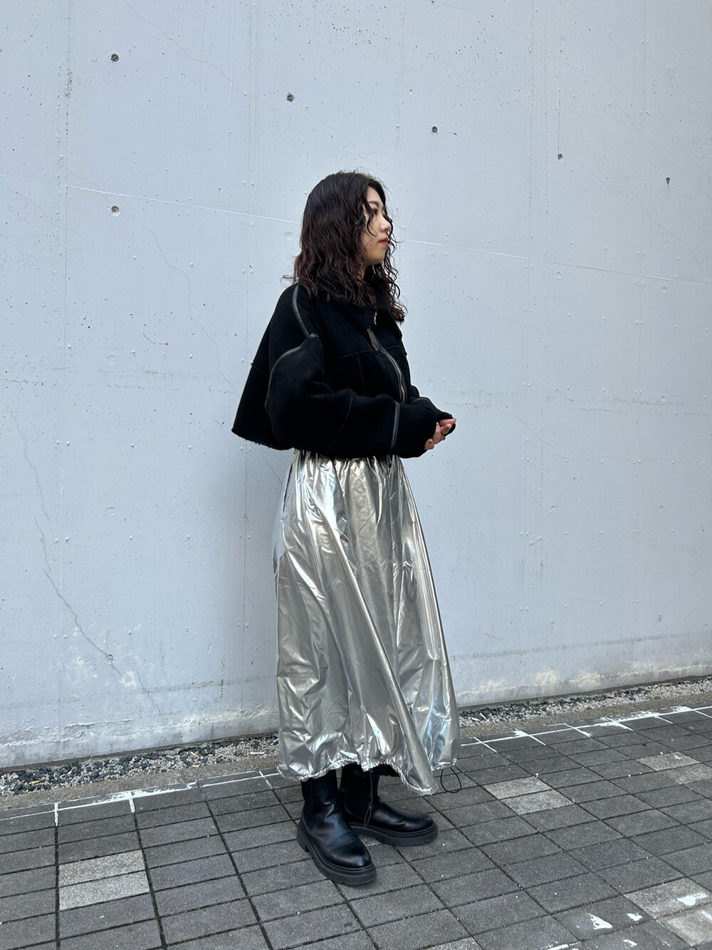 ブラック系のムートンコート、シルバー系のスカートを着用したレディースの秋コーディネートの3枚目の写真