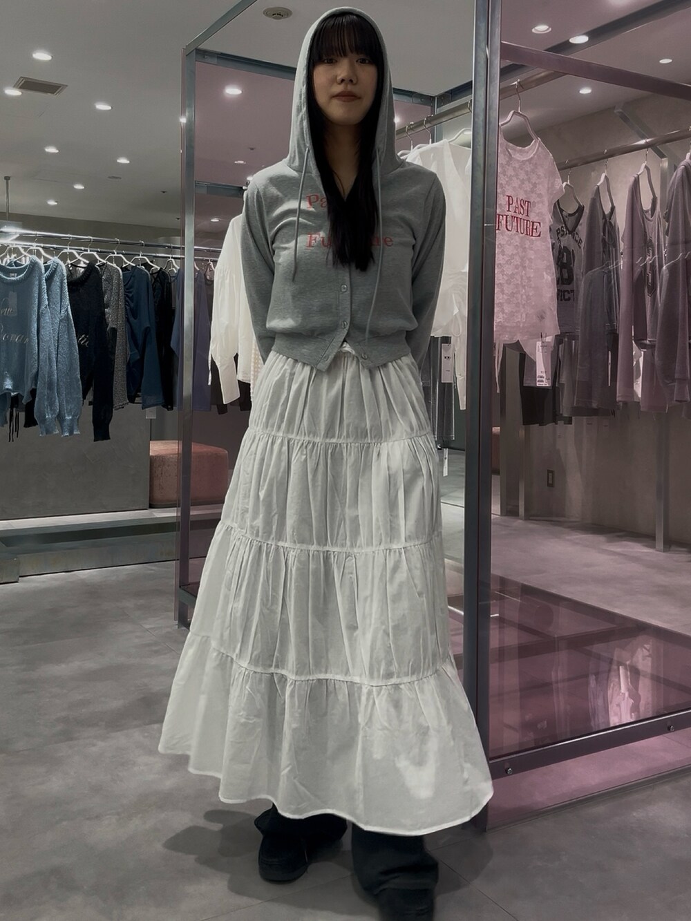 ホワイト系のスカート、グレー系のパーカー、ブルー系のデニムパンツを着用したレディースの春コーディネートの3枚目の写真