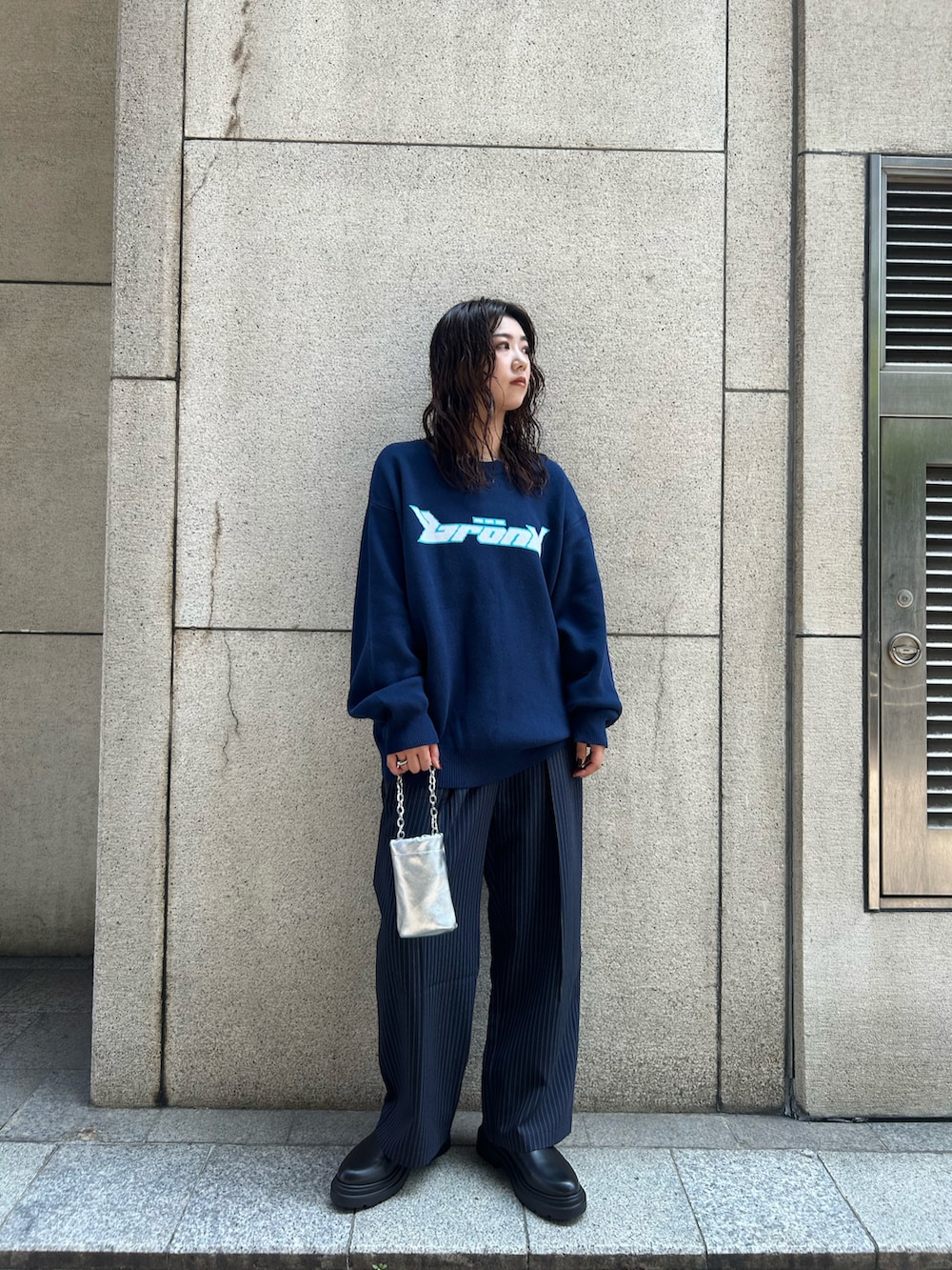 ブルー系のスラックス、ブルー系のニット/セーター、シルバー系のハンドバッグを着用したレディースの夏コーディネートの2枚目の写真