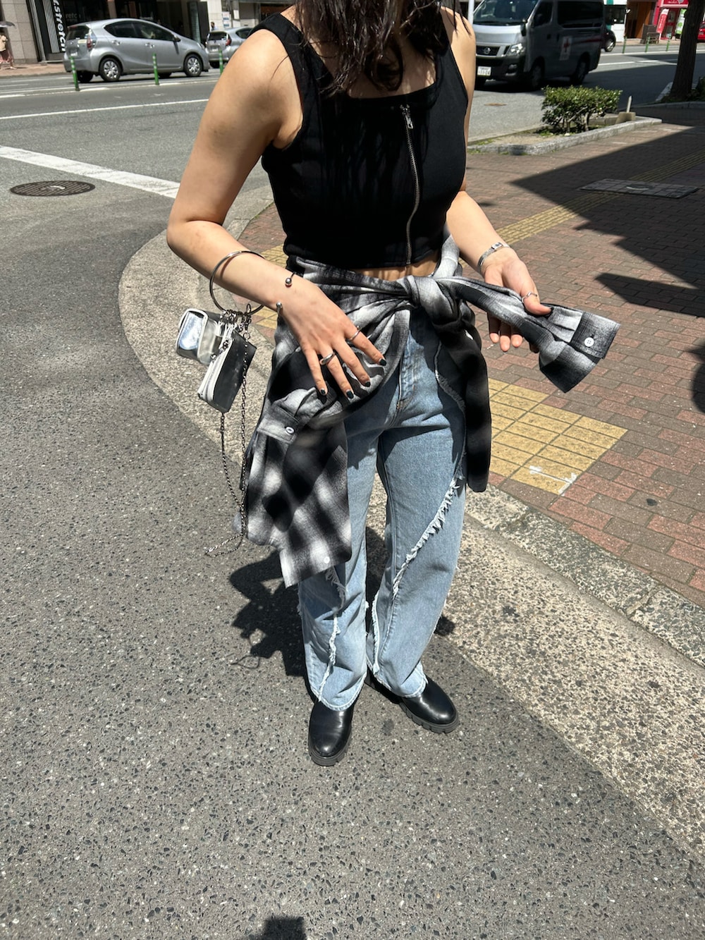 グレー系のタンクトップ、シルバー系のショルダーバッグ、ブルー系のデニムパンツを着用したレディースの春コーディネートの3枚目の写真