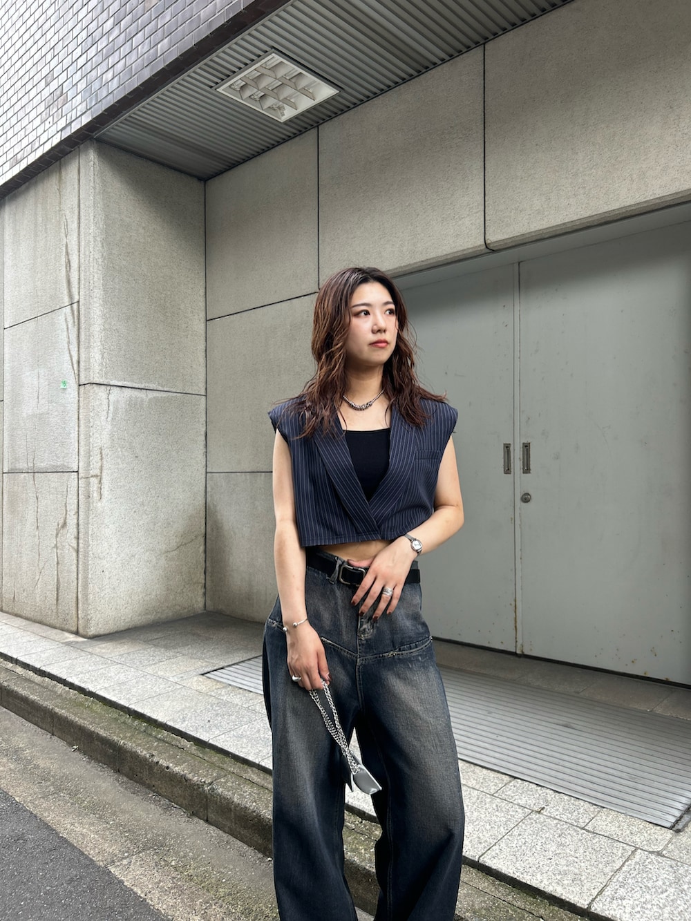 ブルー系のデニムパンツ、グレー系のベスト、ブラック系のショルダーバッグを着用したレディースの秋コーディネートの3枚目の写真