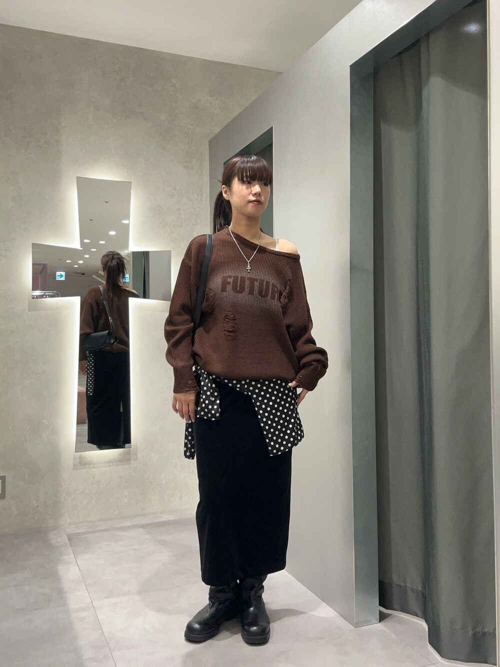 ブラック系のスカート、ブラウン系のニット/セーター、ブラック系のTシャツ/カットソーを着用したレディースの秋コーディネートの2枚目の写真