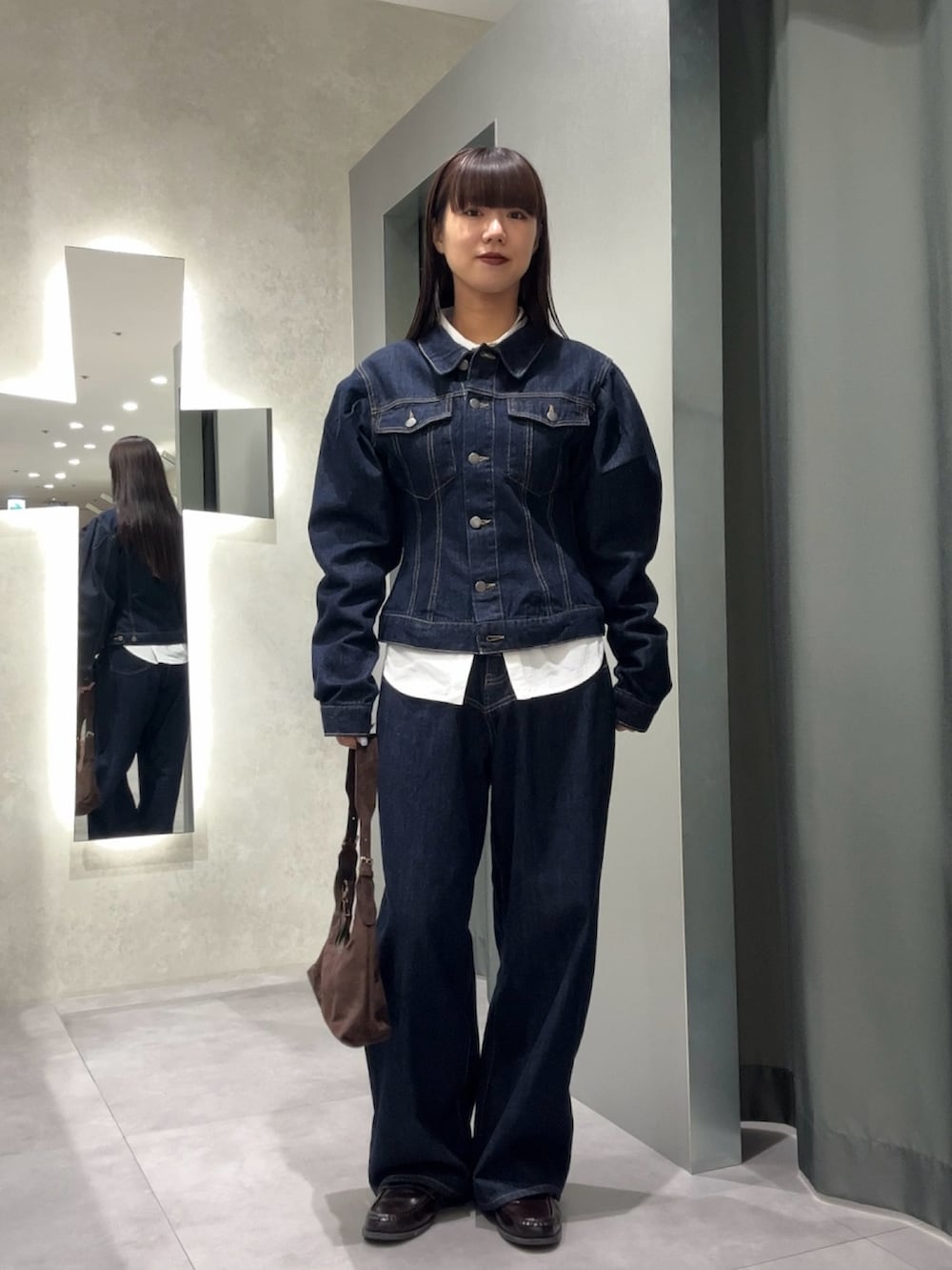 ブルー系のデニムパンツ、ブルー系のデニムジャケット、ブラウン系のトートバッグを着用したレディースの秋コーディネートの2枚目の写真