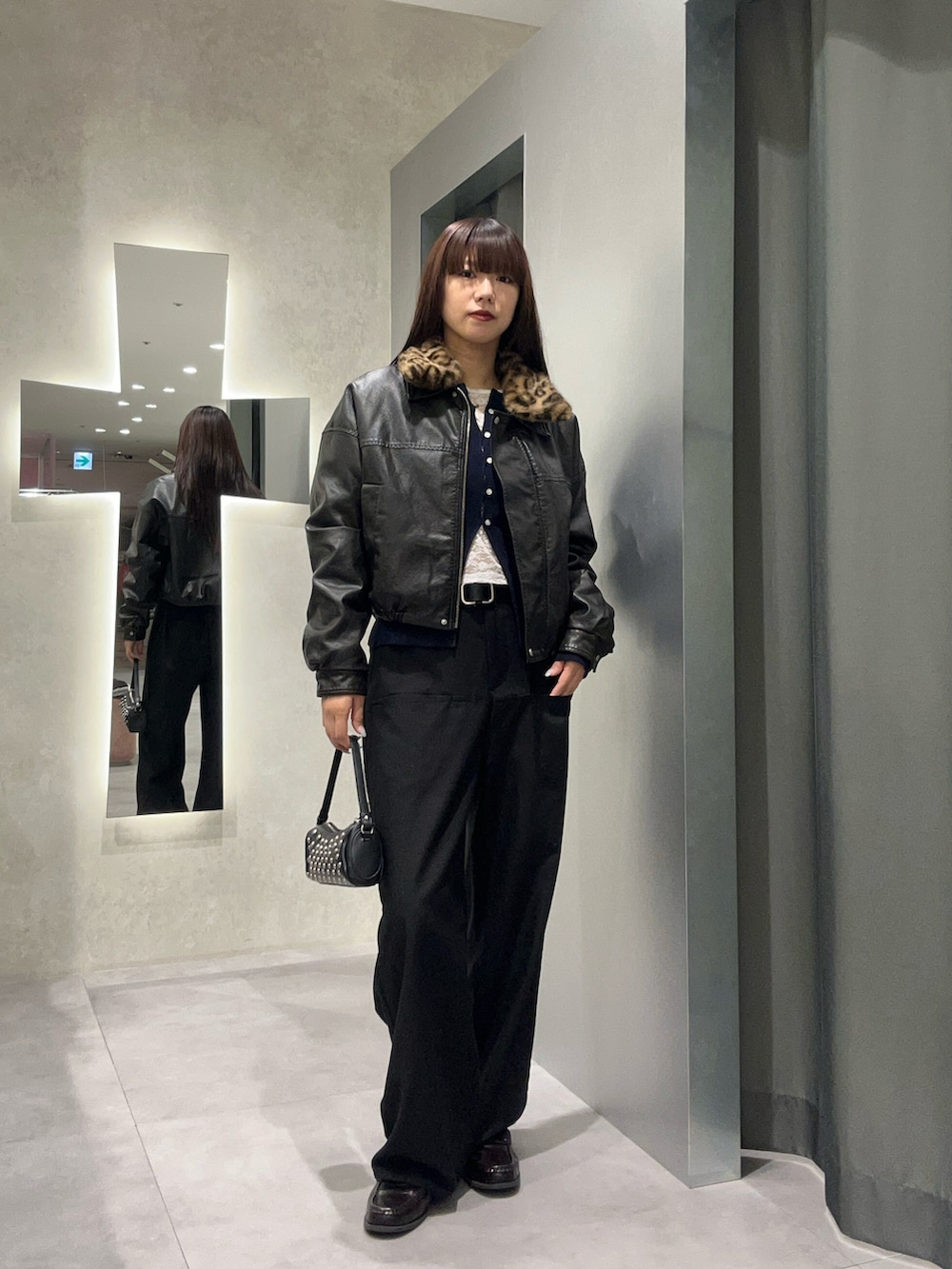 グレー系のスラックス、ブルー系のカーディガン/ボレロ、ブラック系のブルゾンを着用したレディースの秋コーディネートの2枚目の写真