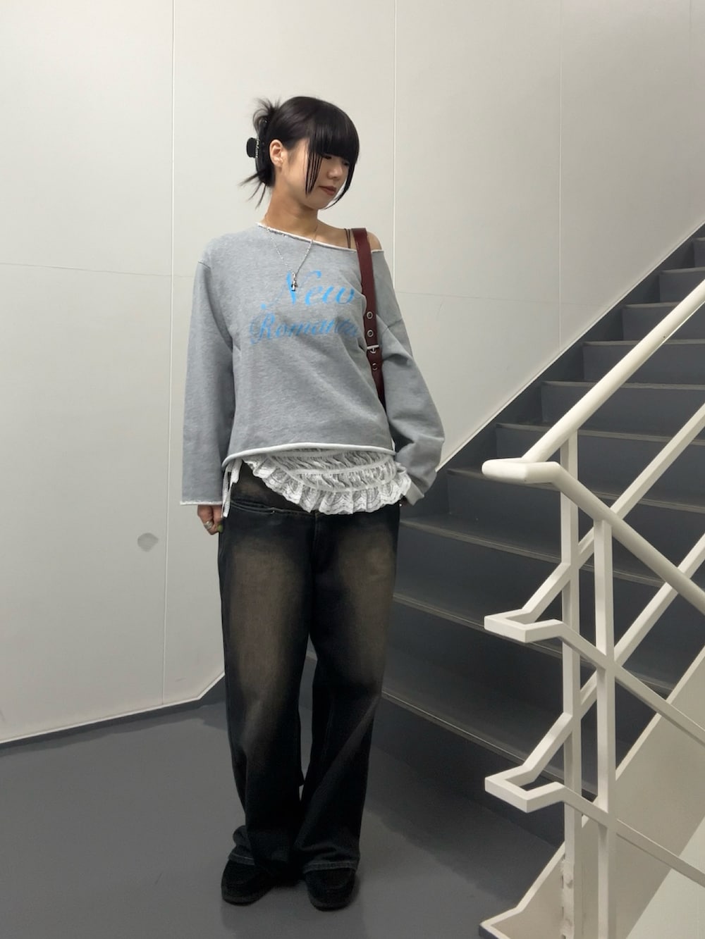 ブラック系のショルダーバッグ、ブルー系のデニムパンツ、グレー系のスウェットを着用したレディースの春コーディネートの3枚目の写真