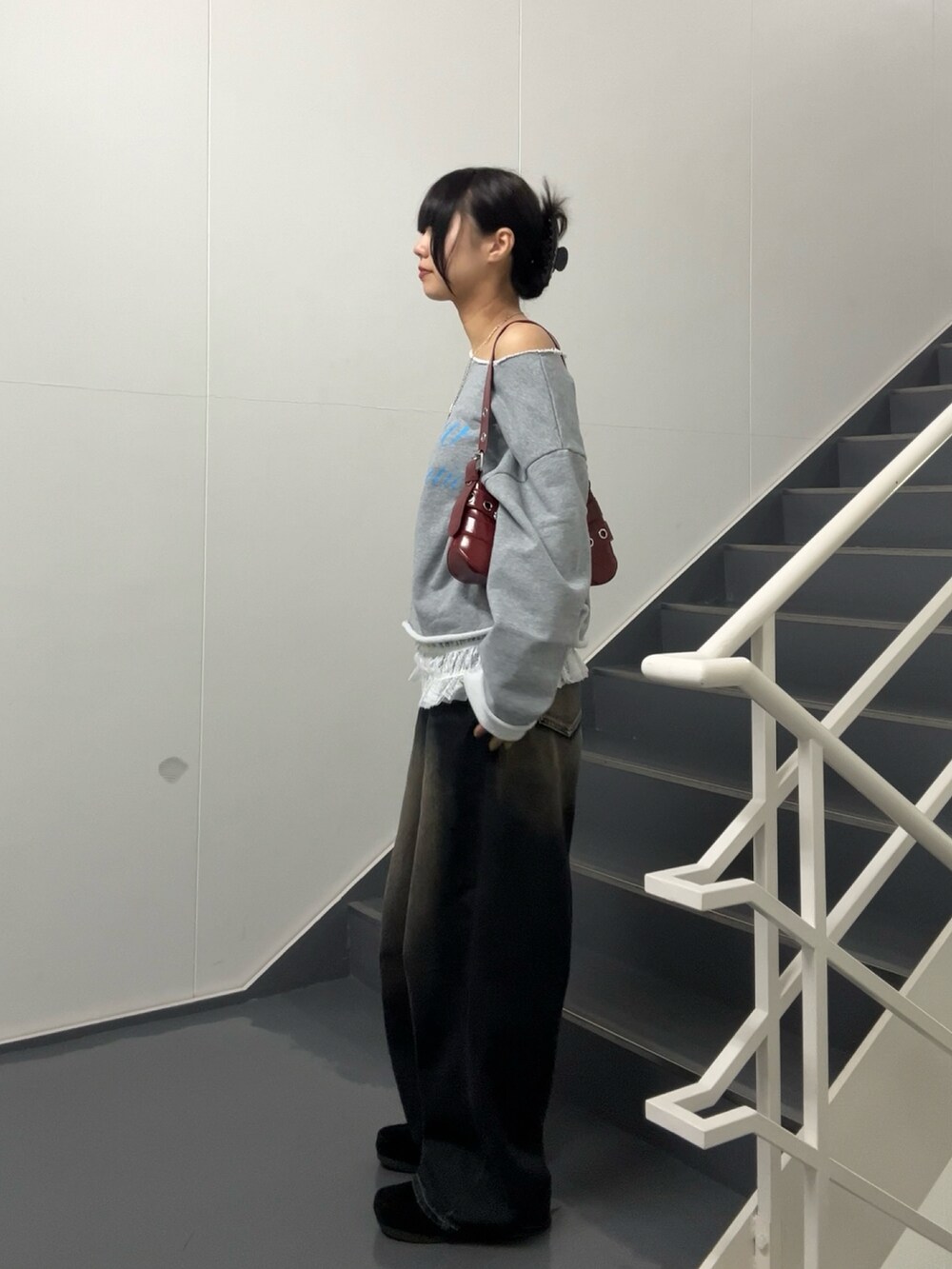 ブラック系のショルダーバッグ、ブルー系のデニムパンツ、グレー系のスウェットを着用したレディースの春コーディネートの2枚目の写真