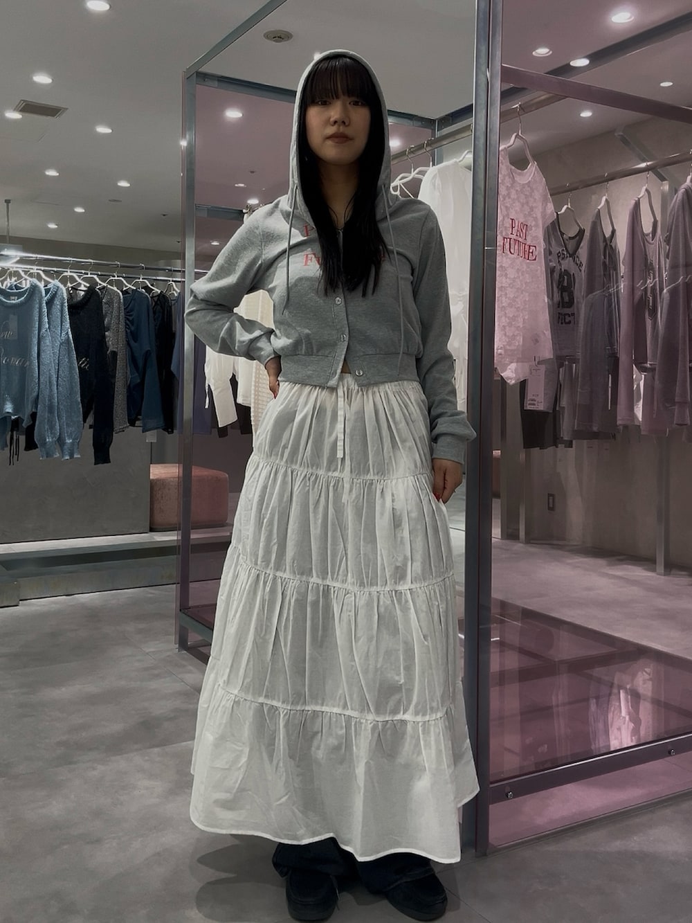 ホワイト系のスカート、グレー系のパーカー、ブルー系のデニムパンツを着用したレディースの春コーディネートの2枚目の写真