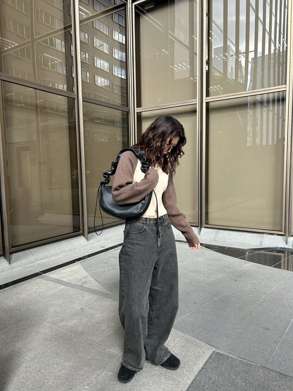 ブラウン系のニット/セーター、ブラック系のショルダーバッグ、ブラウン系のデニムパンツを着用したレディースの秋コーディネートの2枚目の写真