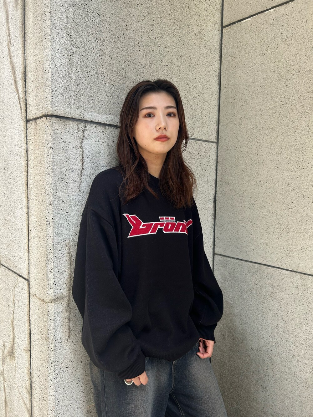 ブルー系のデニムパンツ、ブラック系のニット/セーター、シルバー系のショルダーバッグを着用したレディースの夏コーディネートの3枚目の写真