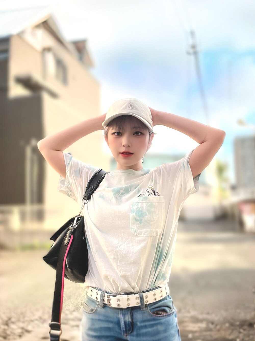 ホワイト系のトップス、ブラック系のボディバッグ/ウエストポーチ、ベージュ系のキャップを着用したレディースの夏コーディネートの3枚目の写真