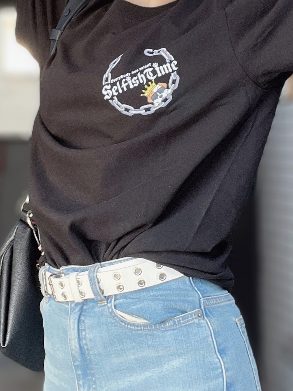 ブラック系のTシャツ/カットソー、ブルー系のデニムパンツ、ブラック系のハンドバッグを着用したレディースの秋コーディネートの2枚目の写真