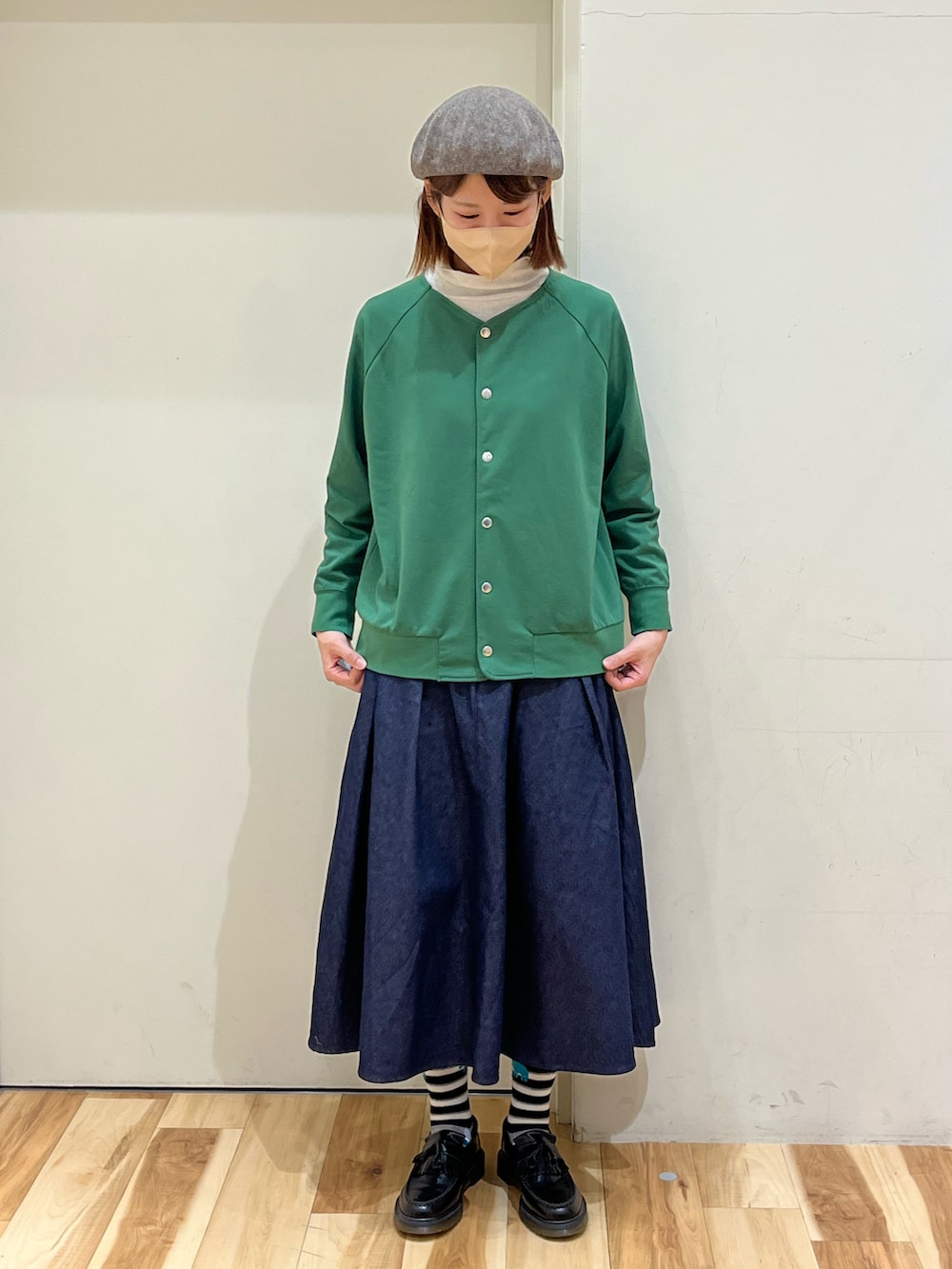 グリーン系のカーディガン/ボレロ、ブルー系のスカート、ブラック系のローファーを着用したレディースの春コーディネートの2枚目の写真