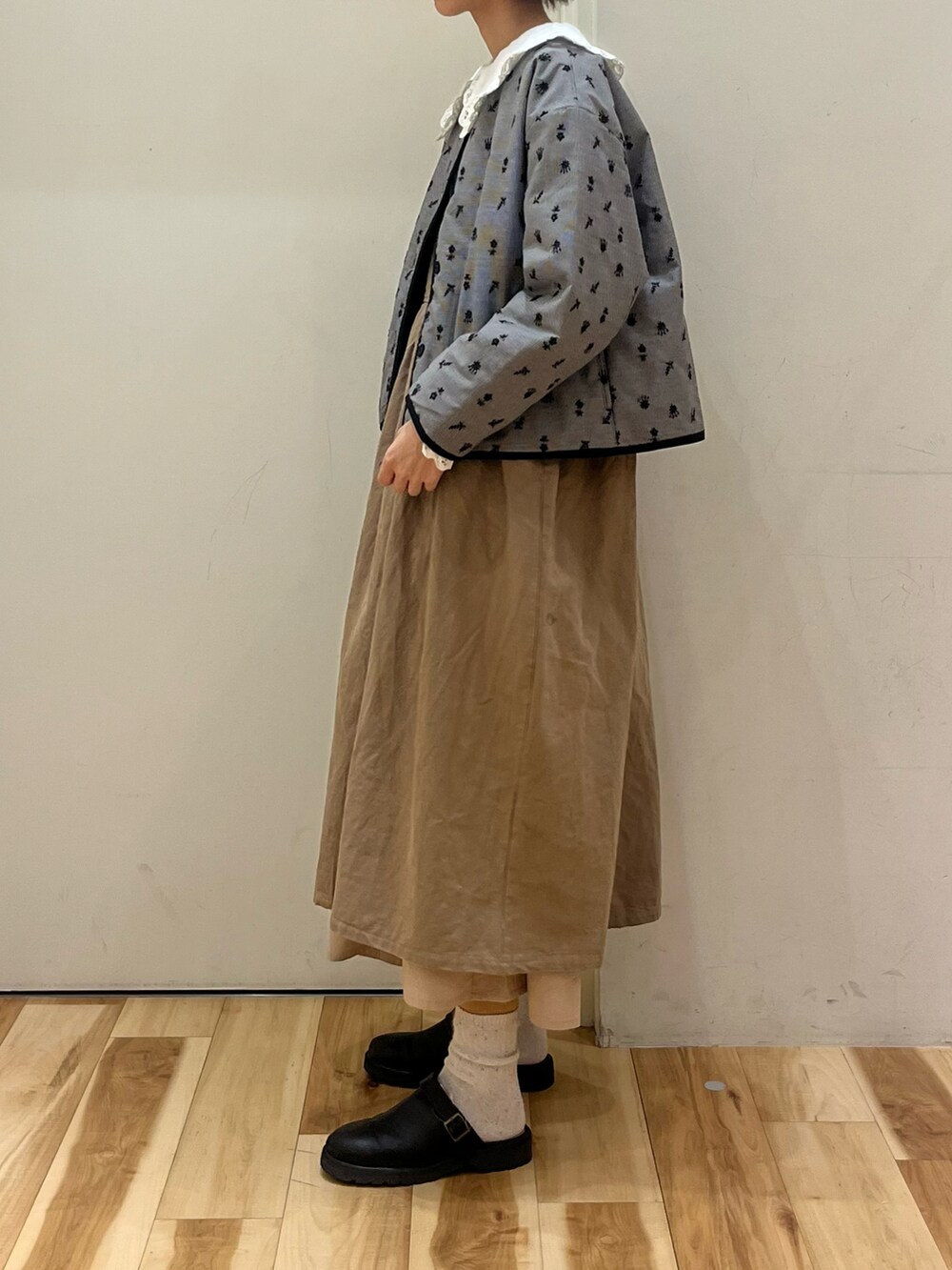 ブラック系のノーカラージャケット、ベージュ系のワンピース、ベージュ系のその他パンツを着用したレディースの冬コーディネートの2枚目の写真