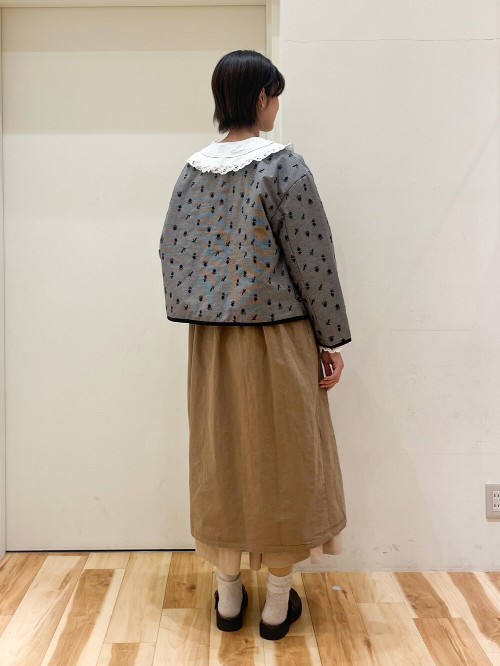 ブラック系のノーカラージャケット、ベージュ系のワンピース、ベージュ系のその他パンツを着用したレディースの冬コーディネートの3枚目の写真