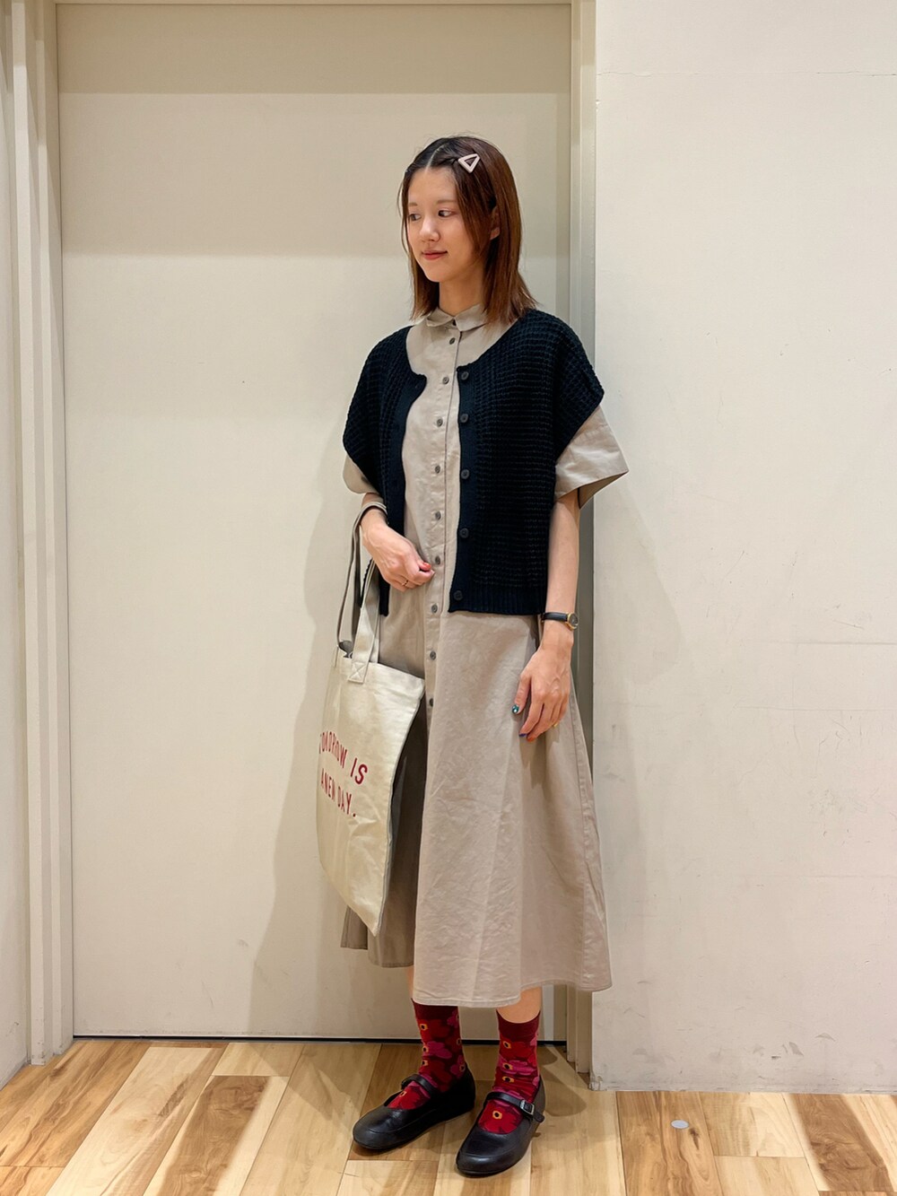 ブラウン系のシャツワンピース、ベージュ系のハンドバッグ、ブラック系のベストを着用したレディースの夏コーディネートの2枚目の写真