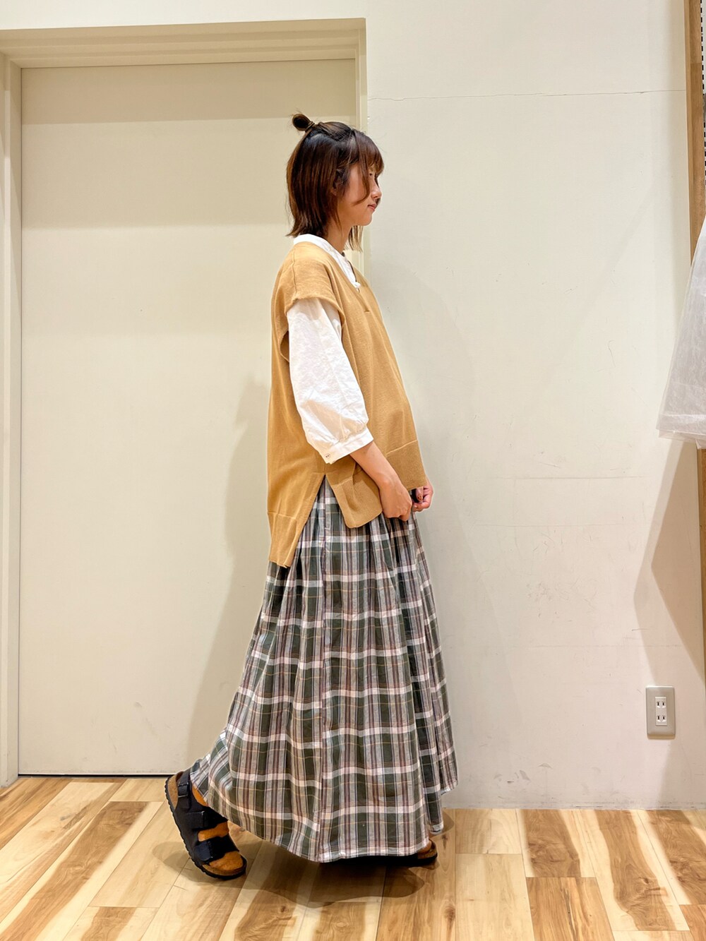 ベージュ系のベスト、ホワイト系のシャツ/ブラウス、グリーン系のスカートを着用したレディースの春コーディネートの2枚目の写真