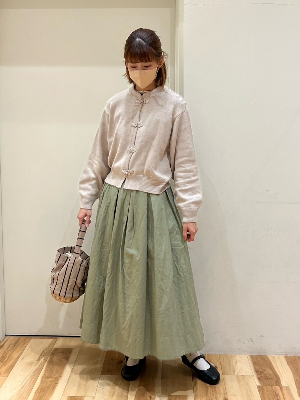 ホワイト系のカーディガン/ボレロ、グリーン系のスカート、ベージュ系のかごバッグを着用したレディースの春コーディネートの2枚目の写真