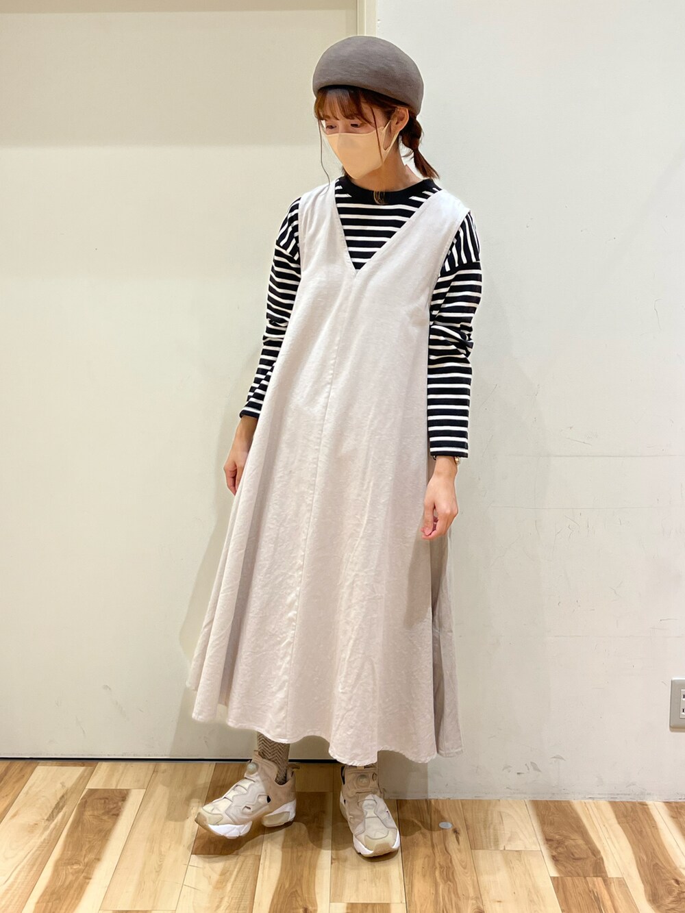 ブラウン系のカーディガン/ボレロ、ブラック系のTシャツ/カットソー、ホワイト系のジャンパースカートを着用したレディースの冬コーディネートの2枚目の写真