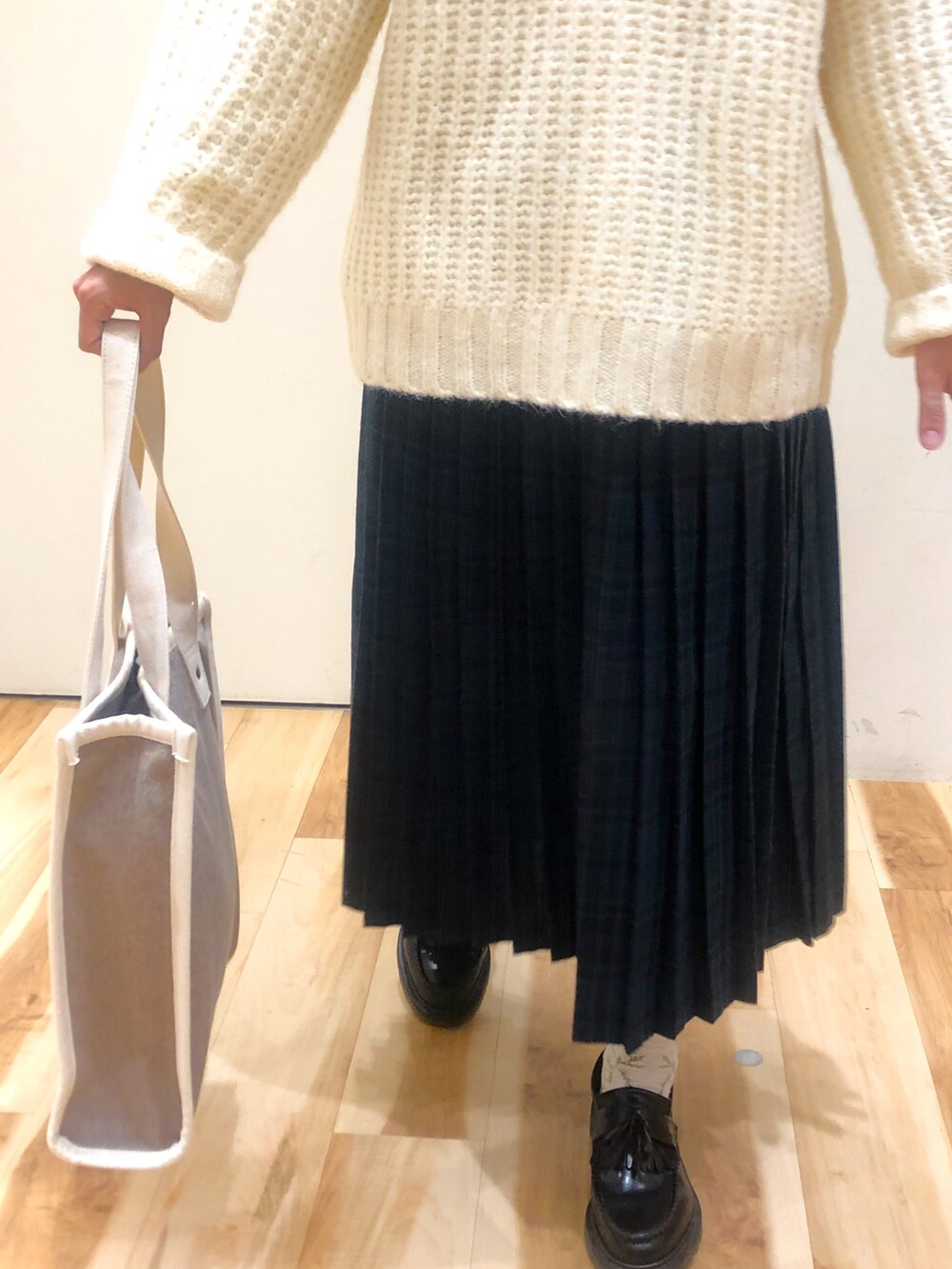 ホワイト系のニット/セーター、ブルー系のスカート、ブラウン系のトートバッグを着用したレディースの冬コーディネートの2枚目の写真