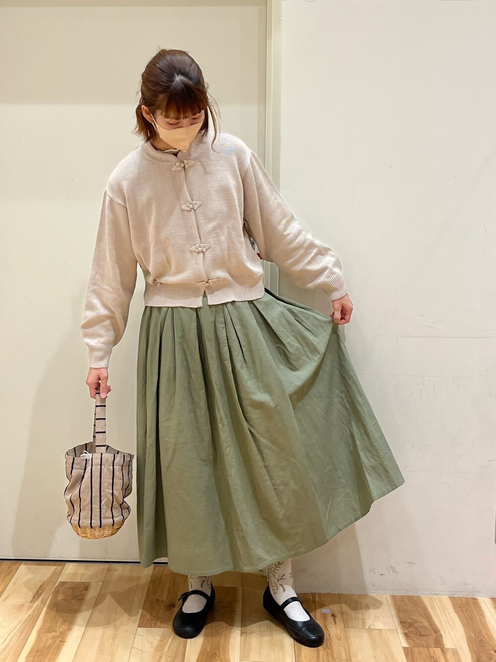 ホワイト系のカーディガン/ボレロ、グリーン系のスカート、ベージュ系のかごバッグを着用したレディースの春コーディネートの3枚目の写真