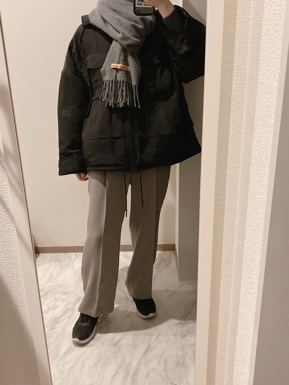 グリーン系のニット/セーター、ベージュ系のパンツ、ブラック系のスニーカーを着用したレディースの冬コーディネートの2枚目の写真