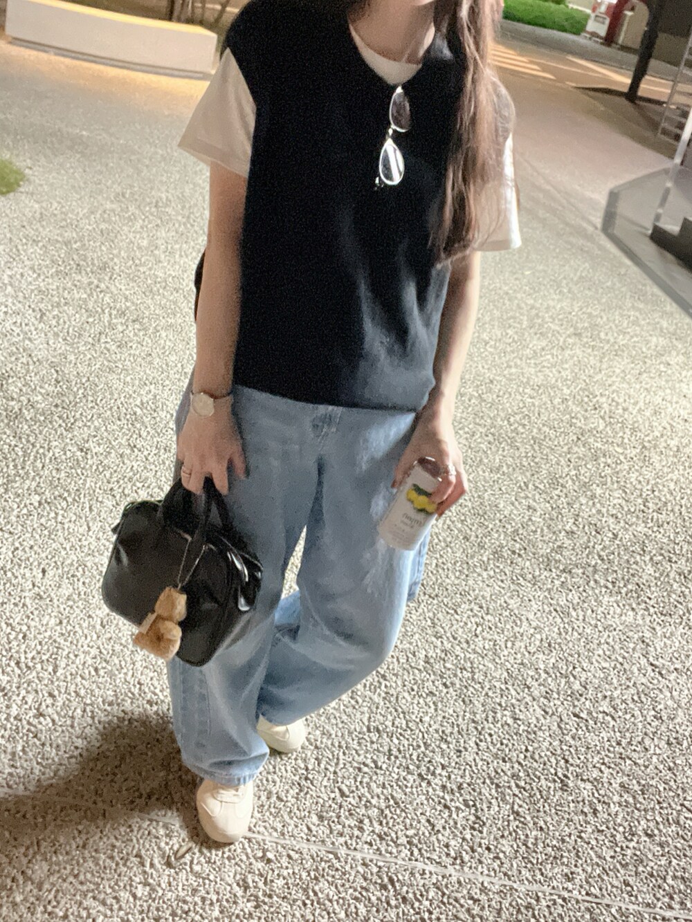 ブルー系のデニムパンツ、ホワイト系のスニーカー、ブラック系のニット/セーターを着用したレディースの秋コーディネートの3枚目の写真