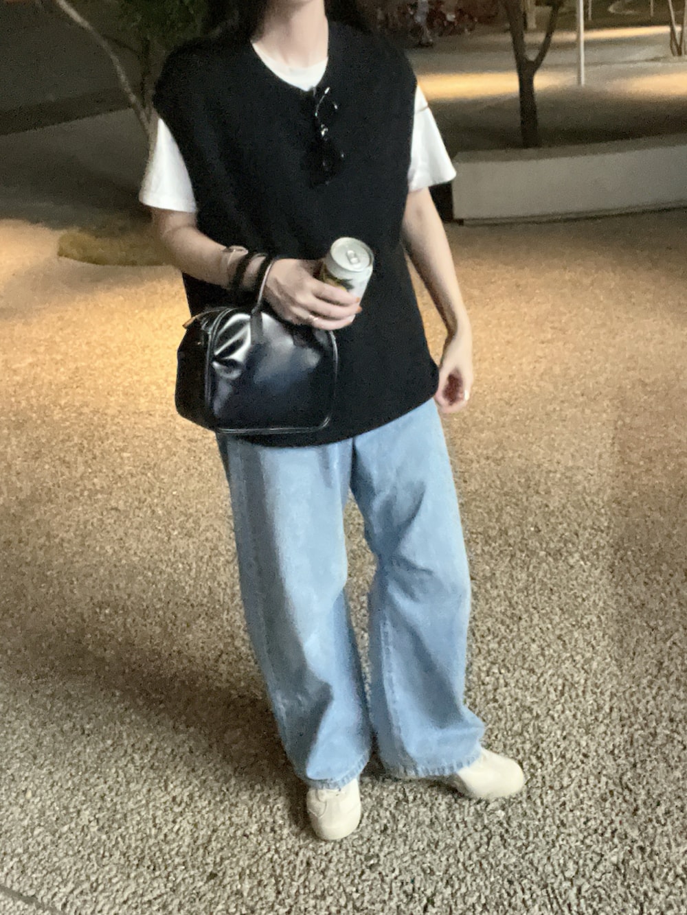 ブルー系のデニムパンツ、ホワイト系のスニーカー、ブラック系のニット/セーターを着用したレディースの秋コーディネートの2枚目の写真